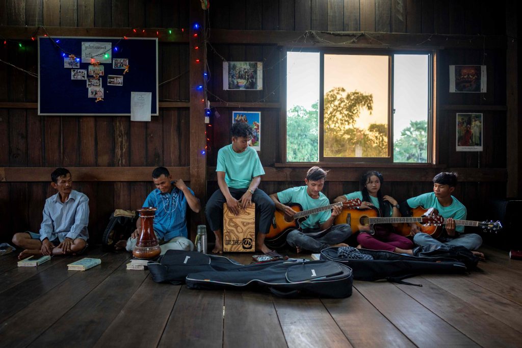 Deltagere i gudstjeneste i huskirke i Cambodja. De spiller forskellige instrumenter.