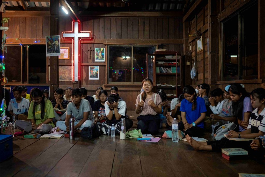 Deltagere i en gudstjeneste i en huskirke i Cambodja. De sidder på gulvet og har lukkede øjne.