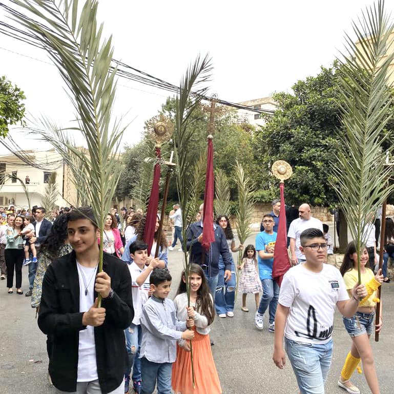 Procession i Beirut i Libanon, hvor deltagerne bærer olivengrene. En deltager bærer et kors. I forgrunden ses børn, der også bærer olivengrene.