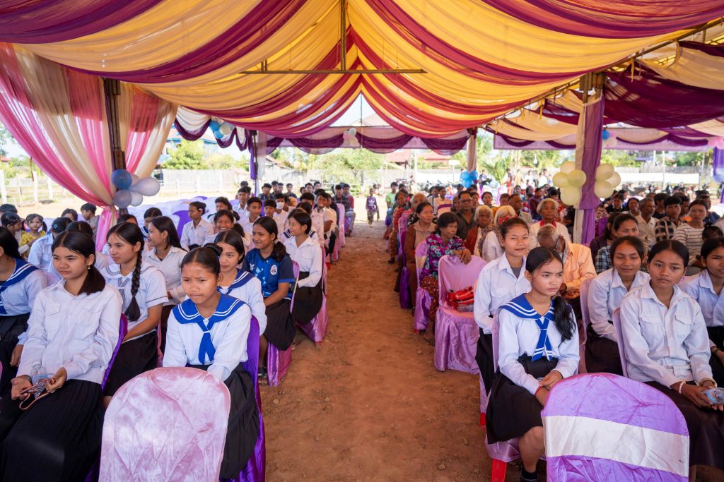 Cambodjanske skoleelever i skoleuniformer sidder på række i et lilla festtelt til fejring af FN's Internationale Menneskerettighedsdag